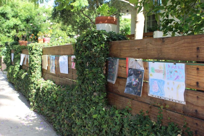 Detail of the children's artwork hanging from a cable on Dan Fields’ Los Feliz fence gallery.