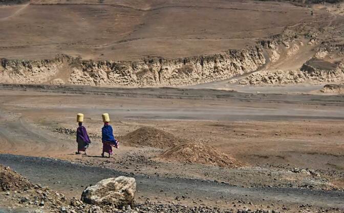 Tanzanian villagers transporting water across arid region. | Anita Ritenour/Some Rights Reserved