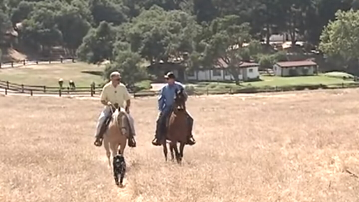 Huell Howser rides on a horse in a dry field | From "Reagan Ranch"
