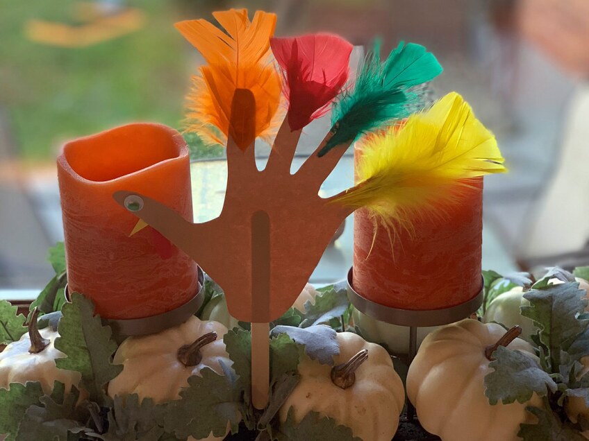 A turkey craft made out of construction paper and feathers.