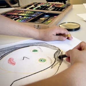 a child draws a self portrait of themselves using crayons.
