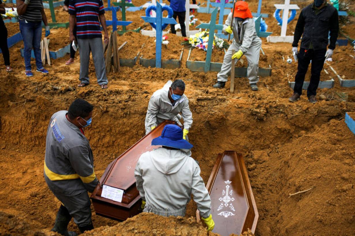 Gravediggers work during a mass burial of people who passed away due to the coronavirus disease (COVID-19), at the Parque Taruma cemetery in Manaus, Brazil May 13, 2020. | REUTERS/Bruno Kelly
