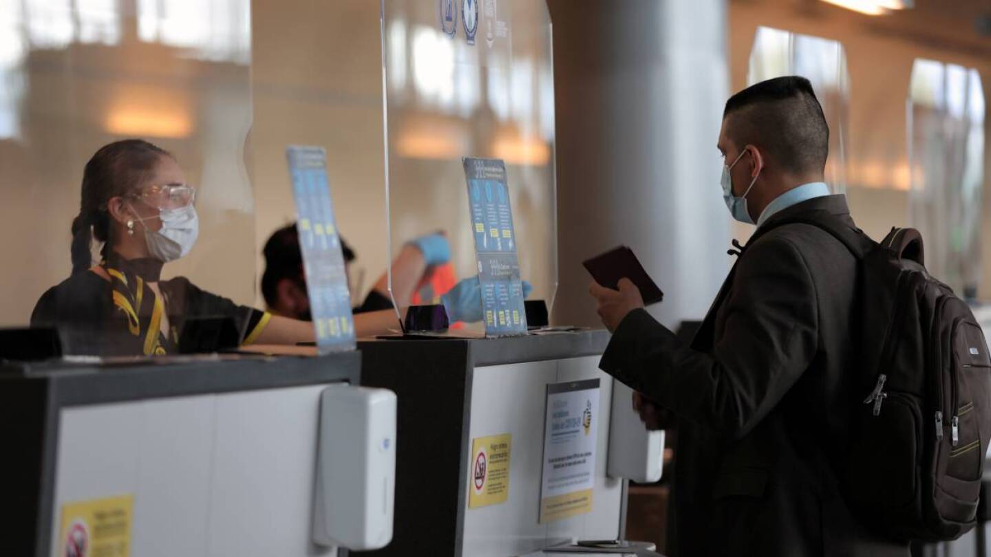 An employee of Spirit airline wearing a face mask asks a passenger for a passport