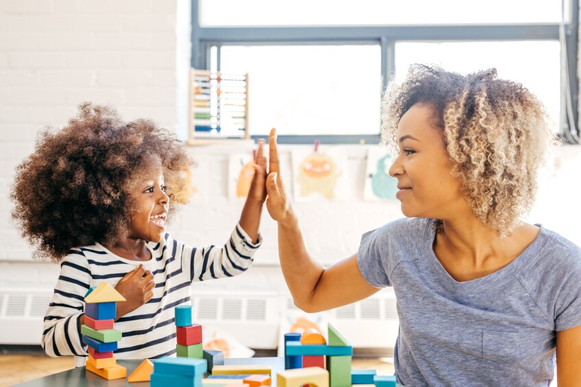 Toddler and mother playing together and giving each other a high five.