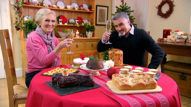 Mary Berry and Paul Hollywood raise their glasses over a spread of Christmas food.