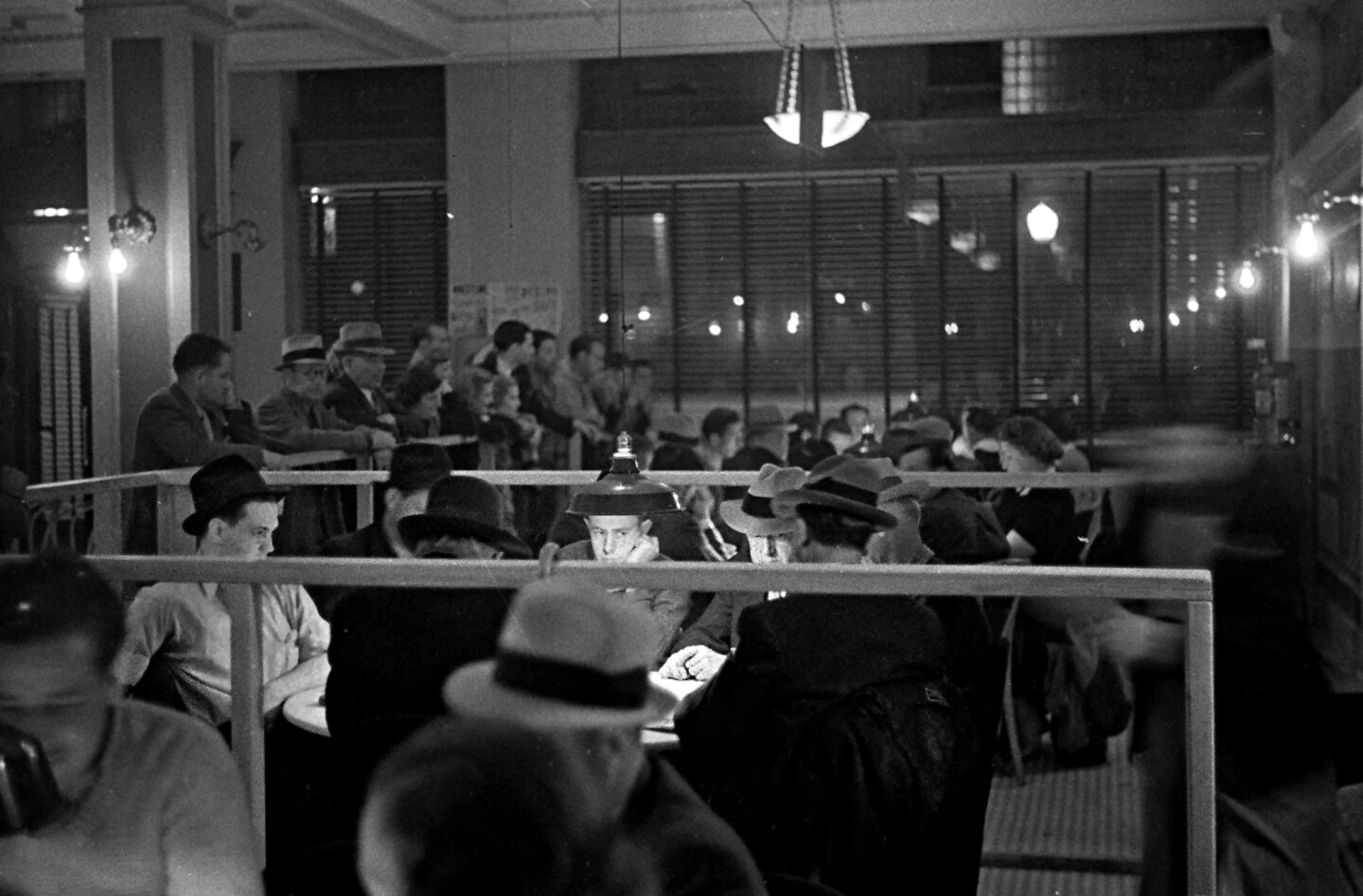 Gamblers playing cards, 1937. While other players wait for a seat, poker players watch the deal with various levels of interest.