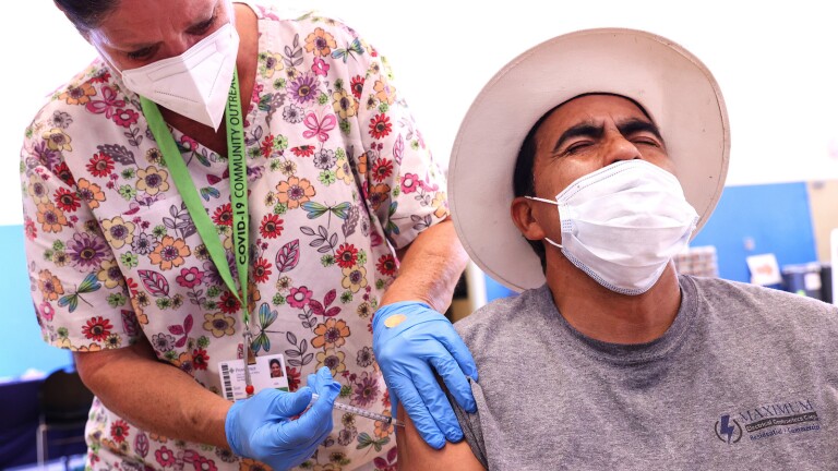 Registered nurse Sue Dillon administers a dose of the Pfizer COVID-19 vaccine to a person at a clinic in Wilmington, California.