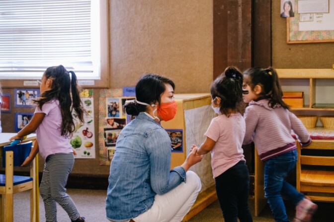 A teacher at Young Horizons Child Development Centers in Long Beach wears a face mask when speaking to her students.