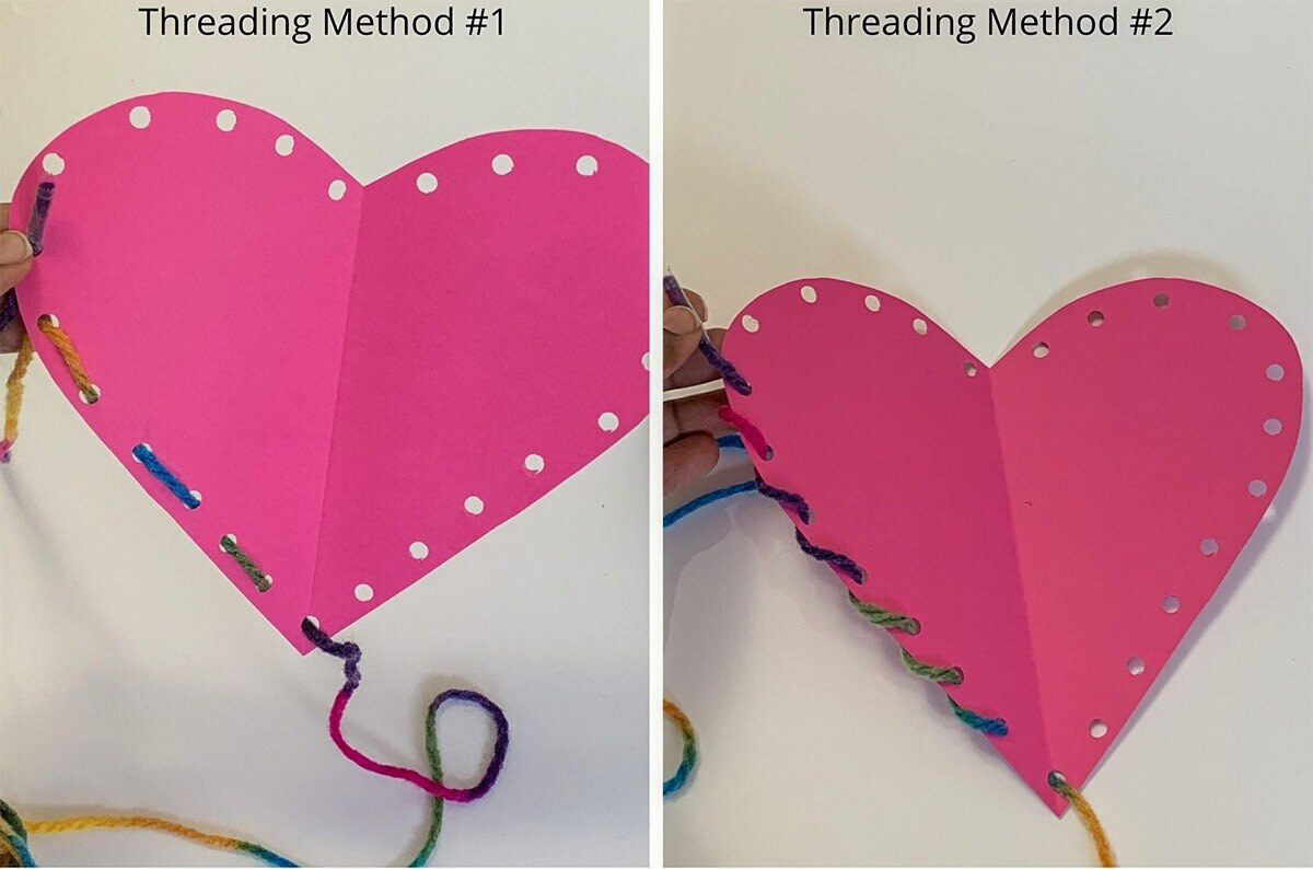 A pink paper heart craft gets threaded with yarn
