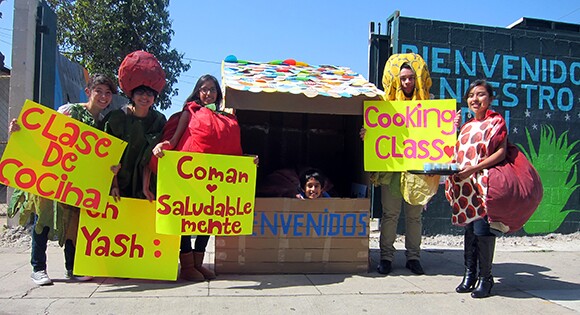 ELARA students Kenia Corral, Lilybeth Hernandez, Karina Pulido, Andy Alvarez and Florisel Rojas surround Yash Songu (inside the hut), prior to a student-led cooking demo at Yash La Casa Market.