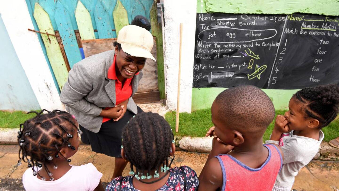 Educator Taneka Mckoy Phipps teaches a lesson with a blackboard painted on a wall, in a low-income neighborhood, during the coronavirus disease (COVID-19) outbreak in Kingston, Jamaica October 27, 2020. October 27, 2020. | REUTERS/Gladstone Taylor