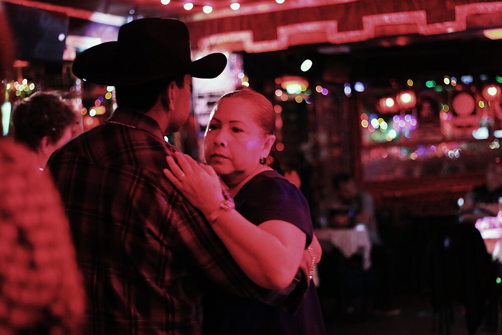 A woman and a man in a hat slow dance.