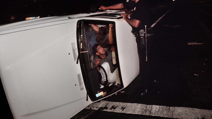 Pacific Division Officer Hoskins tries to pry open the door of a truck involved in a accident that left the driver and passenger locked in the overturned vehicle. | Joseph Rodriguez