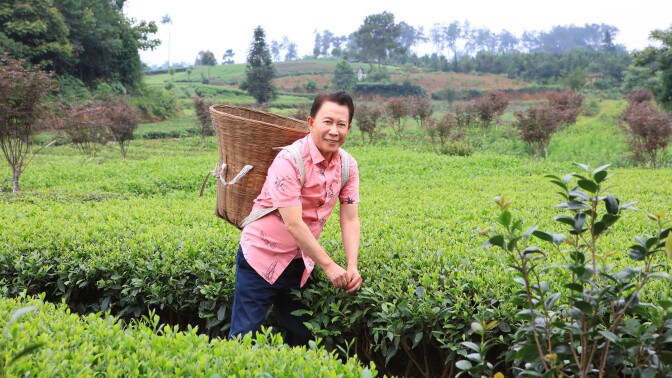 Chef Martin Yan in a field shoulders a wicker basket.