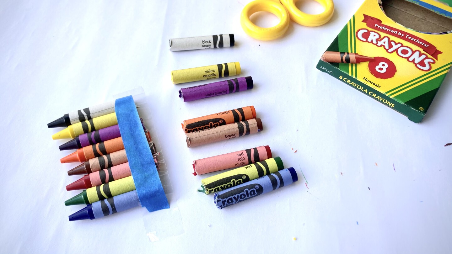 Crayons are cut in half. The tops are held together lined up with tape a the bottom.