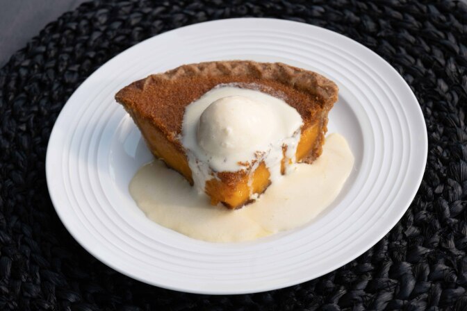 A orange colored pie topped with ice cream