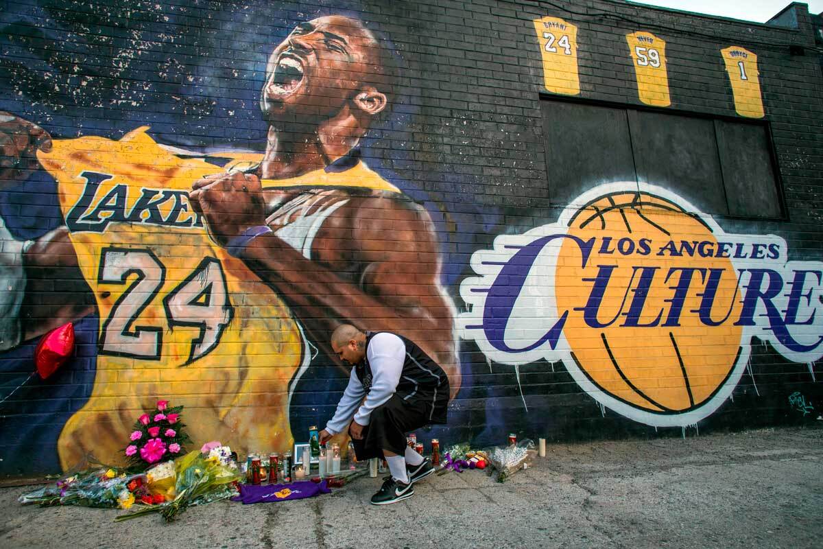 Luis Villanueva lights a candle in front of a Kobe Bryant mural in downtown Los Angeles on January 26, 2020 | APU GOMES/AFP via Getty Images