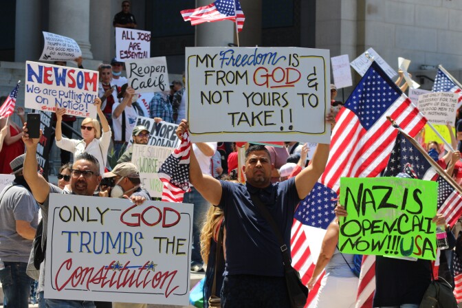 Man holding sign reading, "My freedom is from God and is not yours to take"