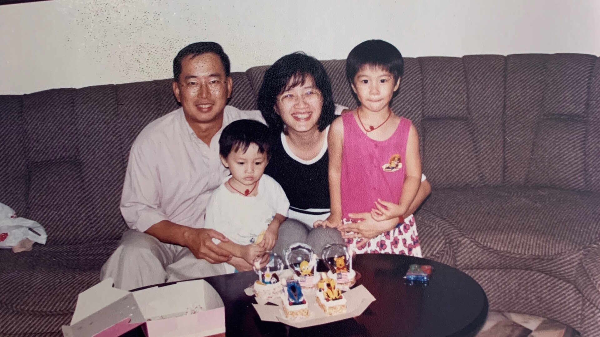 A family, a mother, father and two children, sit on a couch