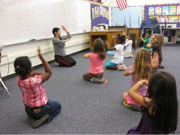 Teaching Artist Viviana Alcazar helping children warm up for a dance class.