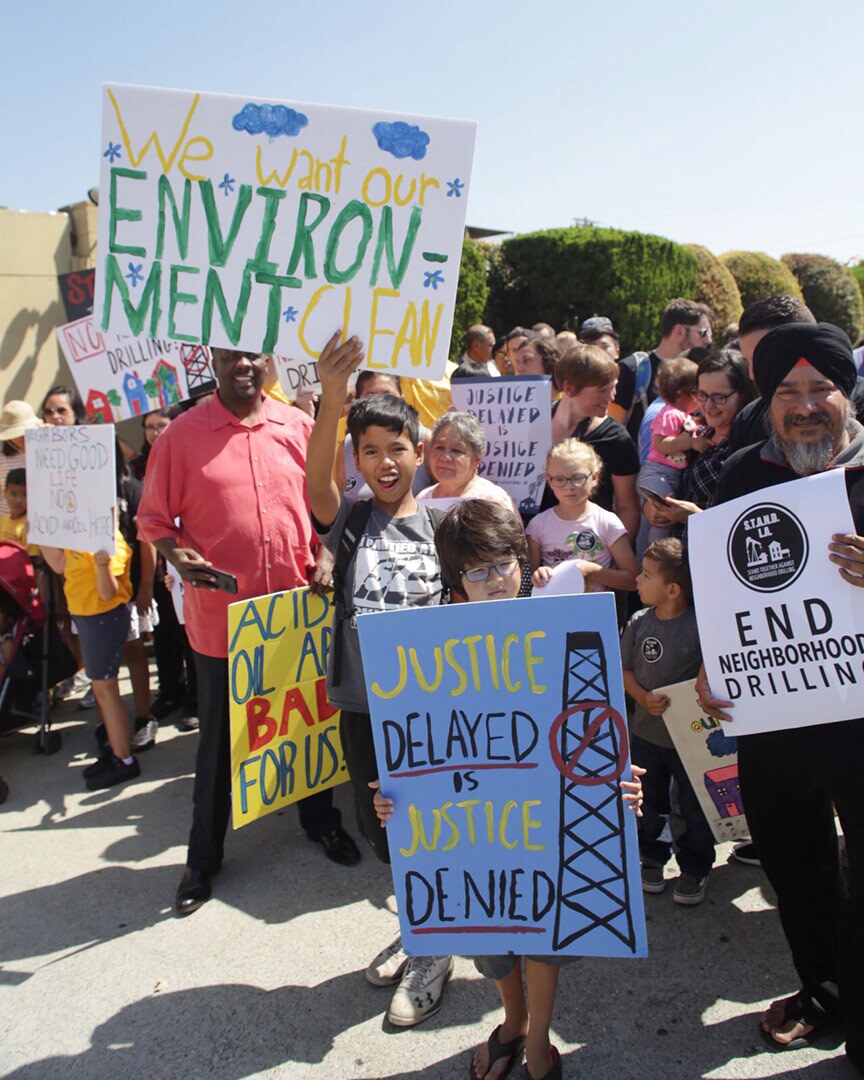 A group of people protest against neighborhood drilling.