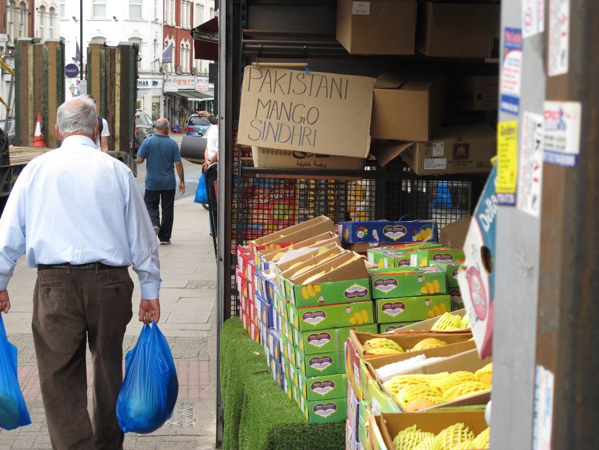 A resident passes a display of Pakistani mangoes for sale in the Tooting neighborhood of London, June 15, 2020. | Thomson Reuters Foundation/Laurie Goering