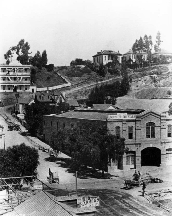 J. G. de Turk's Livery, Feed and Sale Stable, seen here circa 1884-91, stood catercorner to a saddlery and harness shop at First and Broadway. Courtesy of the USC Libraries - California Historical Society Collection.