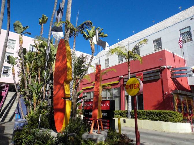 "Surfboard Tiki" by Peter Shire is a red, yellow and orange sculpture shaped like a Tiki head and surfboard.