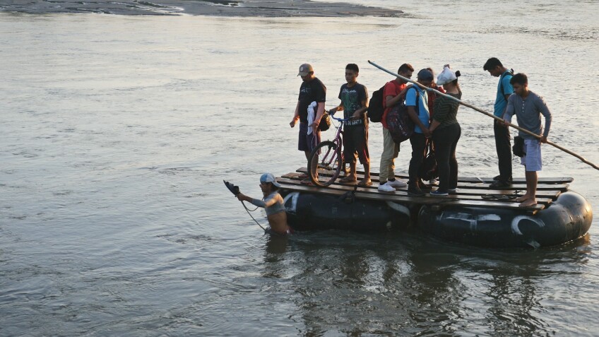 Migrants cross a river on a raft. | Still from "Global Mosaic" film "Migrant Journeys"