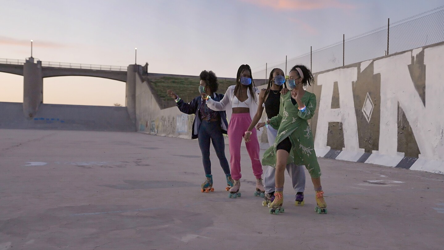 Four young women in rollerskates wearing face masks at Sepulveda Dam.