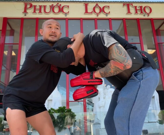 MMA fighter Ron Scolesdang, left, teaches a class of seniors how to knee his sparring partner.