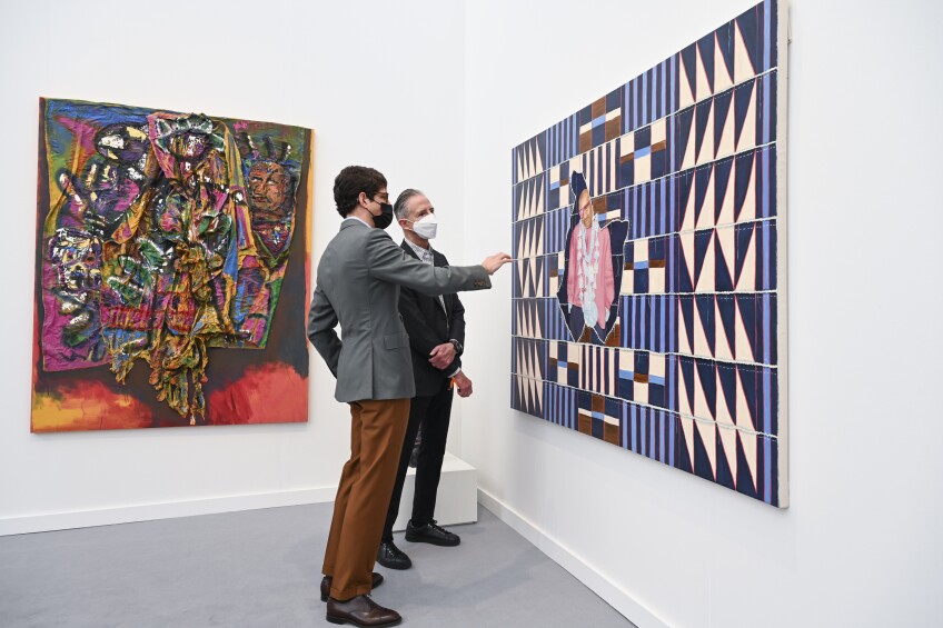 Two men in suits and face masks discuss