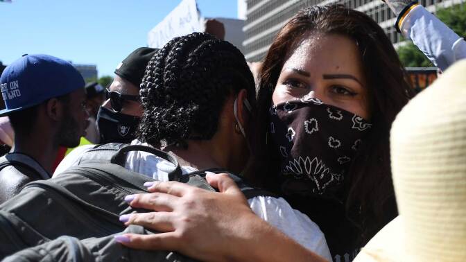 Protestors hug at the Brown Unity March, which was organized to unite the Black, Latino and Indigenous communities in demanding justice for victims of police brutality in Los Angeles. | ROBYN BECK/AFP via Getty Images