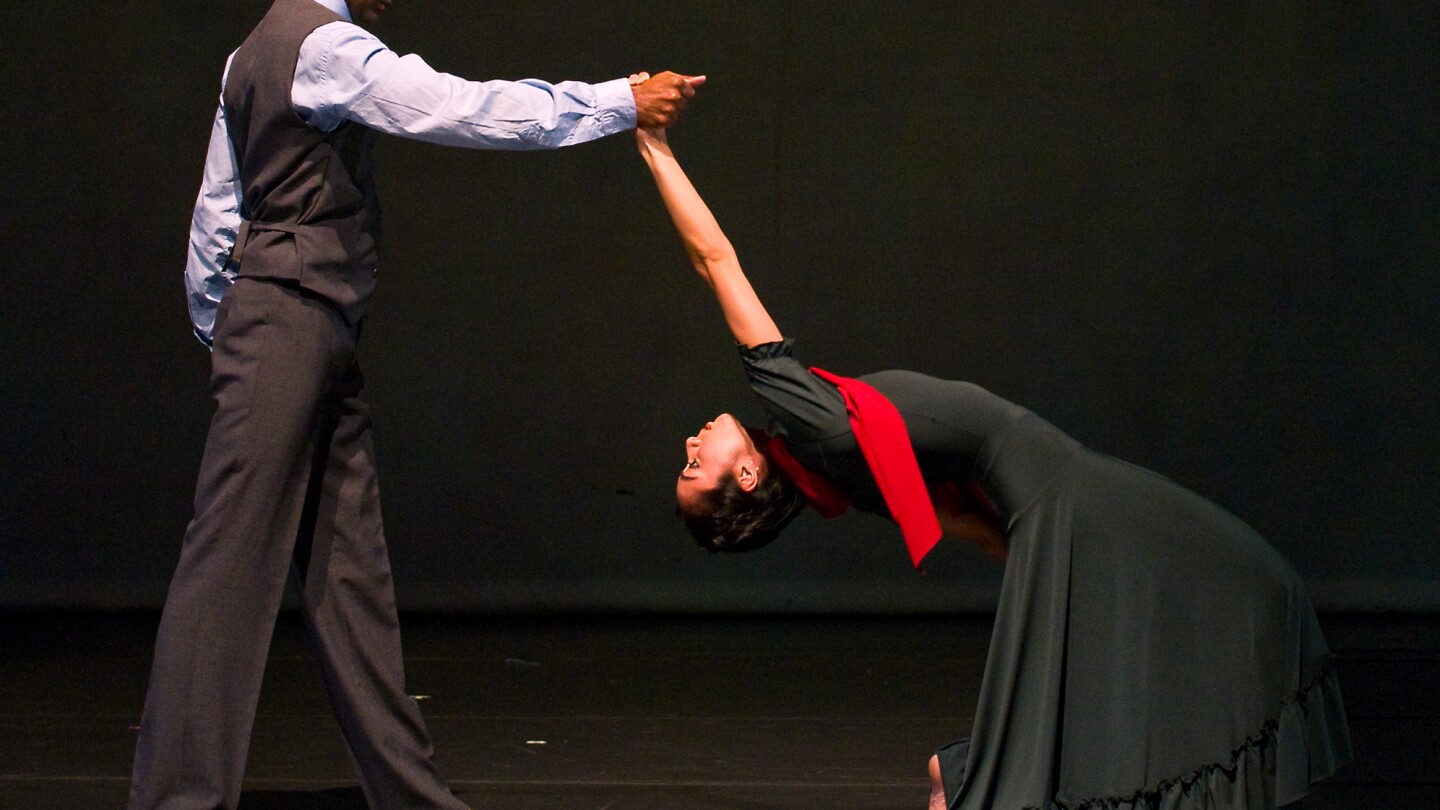 A barefoot man and woman dance together.