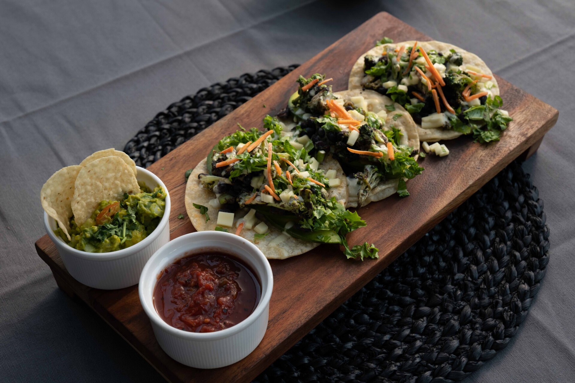 Three tacos on a tray with chips and dip.