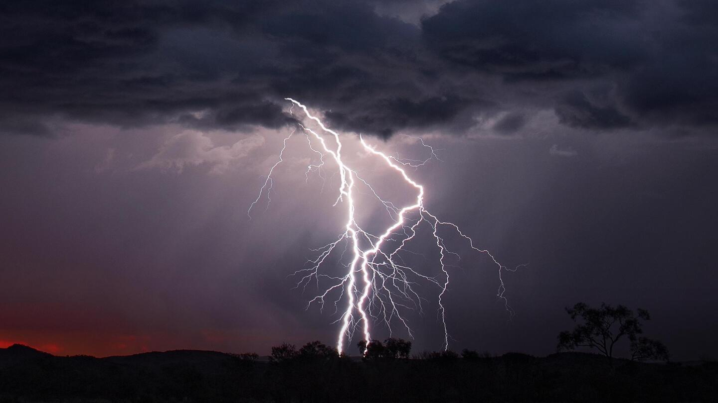 A night photo of lightning striking in the distance.