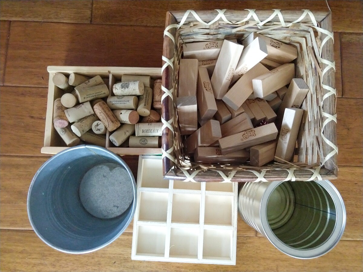 Two small containers filled with small wooden blocks alongside two cups and an ice cube tray.