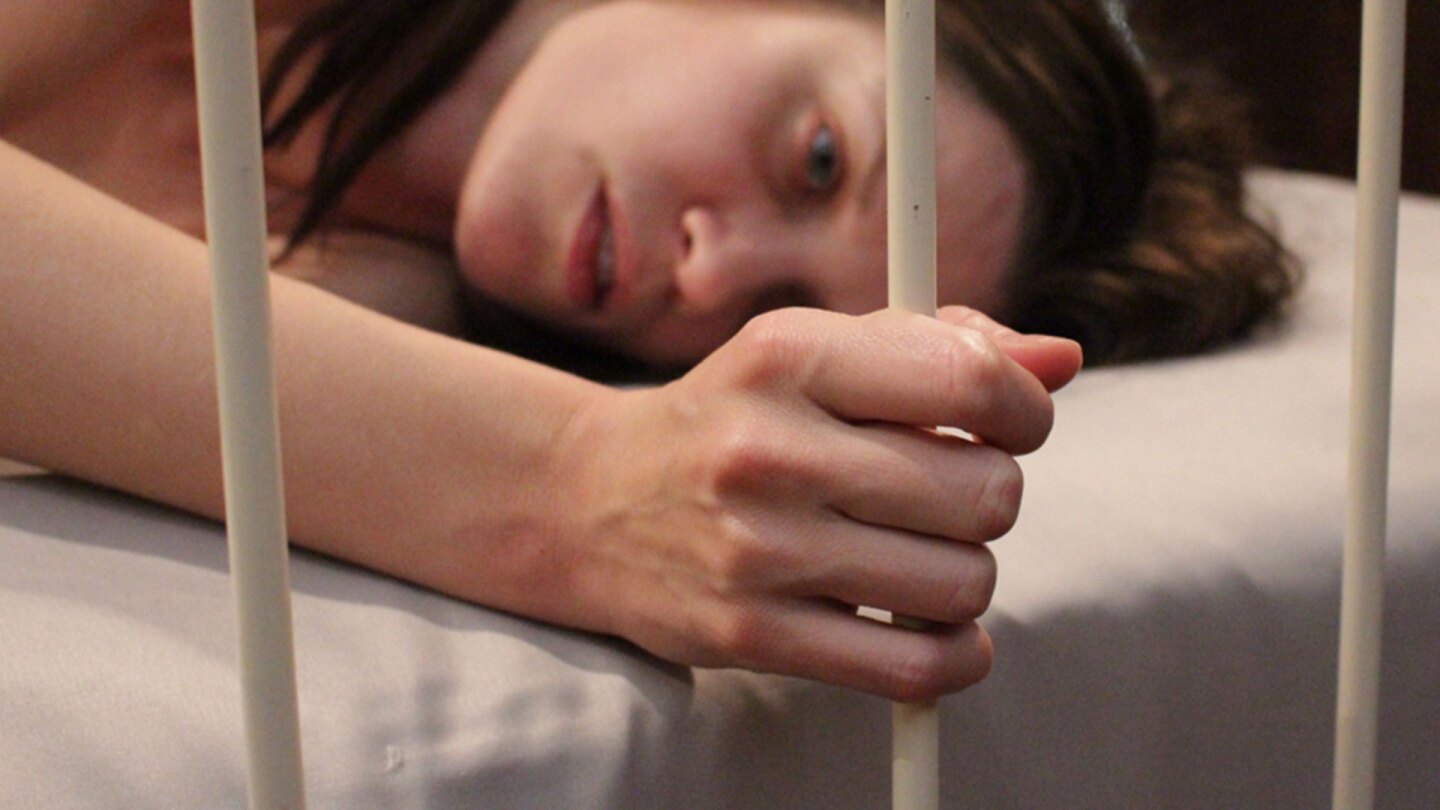 Still of Frida holding a bed frame from "Apartment 407." | Development Hell Pictures/Gravitas Ventures