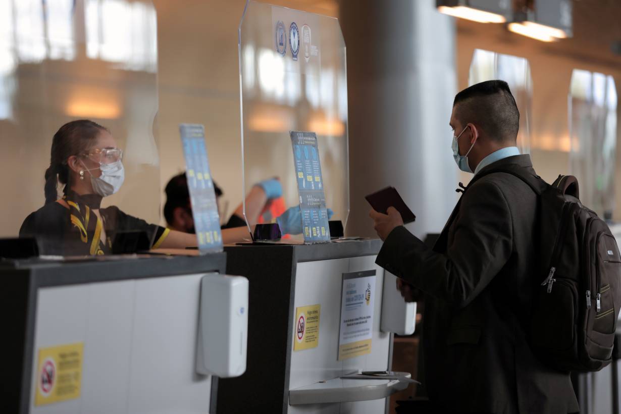 An employee of Spirit airline wearing a face mask asks a passenger for a passport