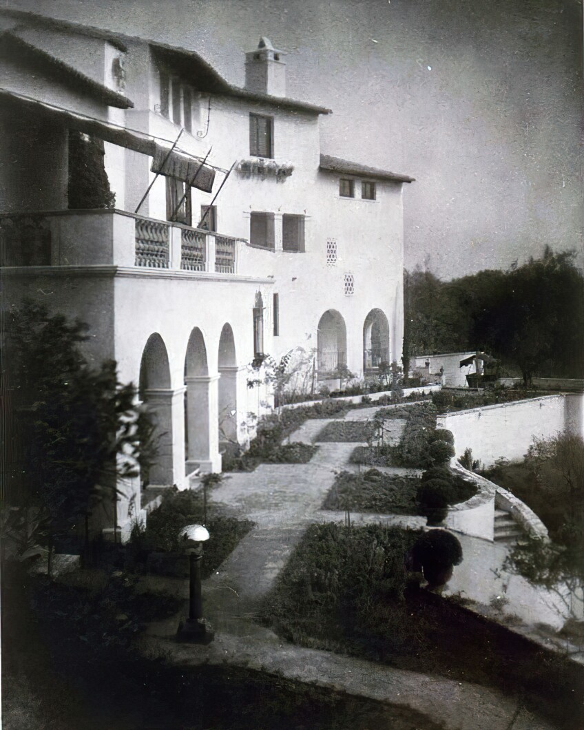 A black and white photo of the Villa Aurora, a majestic Spanish Revival style mansion with beautifully manicured gardens surrounding it.
