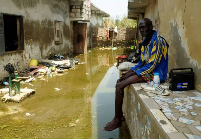Issa Camara sits in the flooded alley of his home after heavy rains in Yeumbeul district on the outskirts of Dakar, Senegal, September 15, 2020. | REUTERS/Christophe Van Der Perre