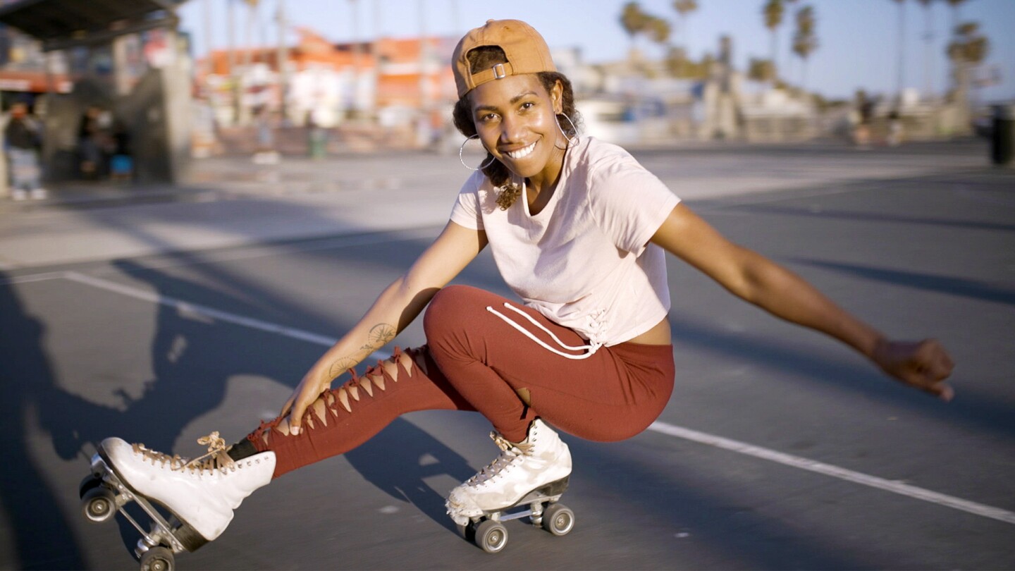 A young woman smiles at the camera with roller skates on.