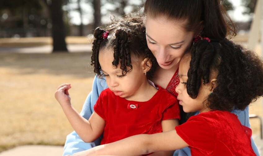 A woman reads with two little girls