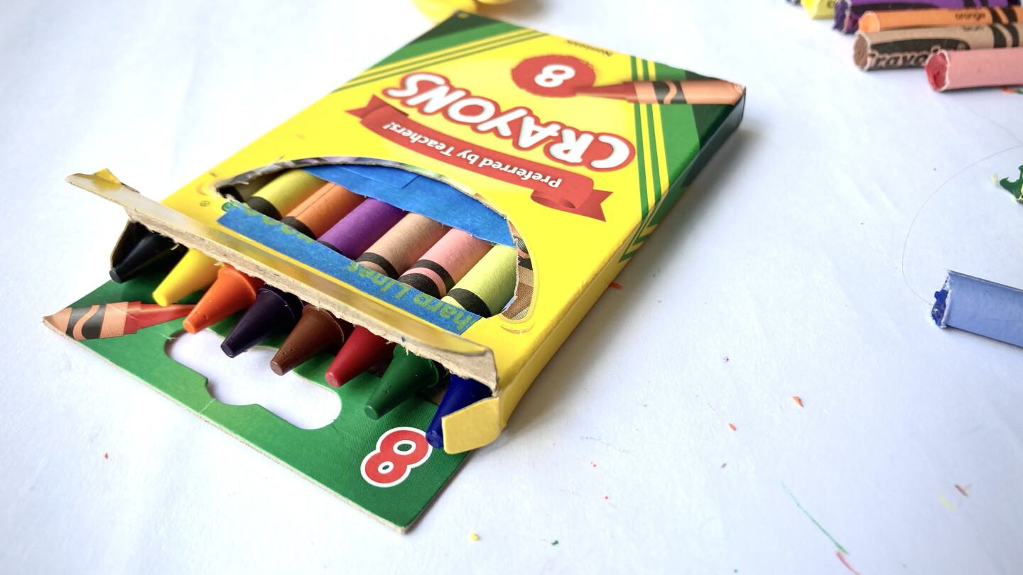 A box of crayons with a small hole cut in the front so the tops of the crayons are visible.