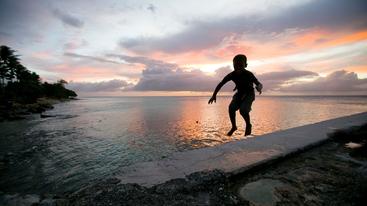 A little boy jumps near the ocean surrounding the Marshall Islands, which are at high risk due to sea level rise. | Courtesy of Thomson Reuters Foundation