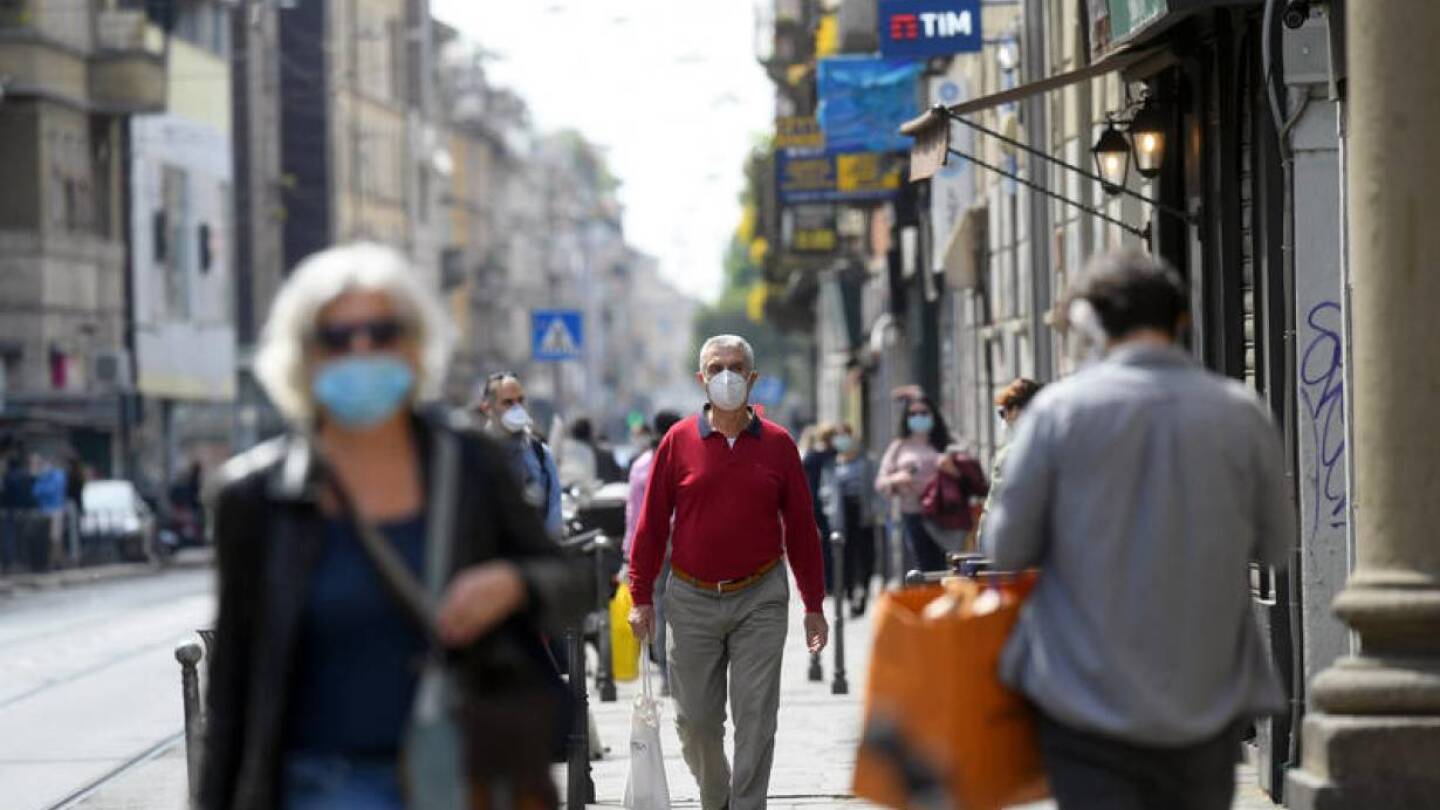 People wearing protective masks walk in an increasingly busy street, amid the coronavirus disease (COVID-19) outbreak, in Milan, Italy April 18, 2020. | REUTERS/Daniele Mascol