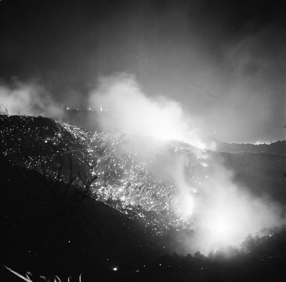 black and white photo of fire on a mountain shot from a distance