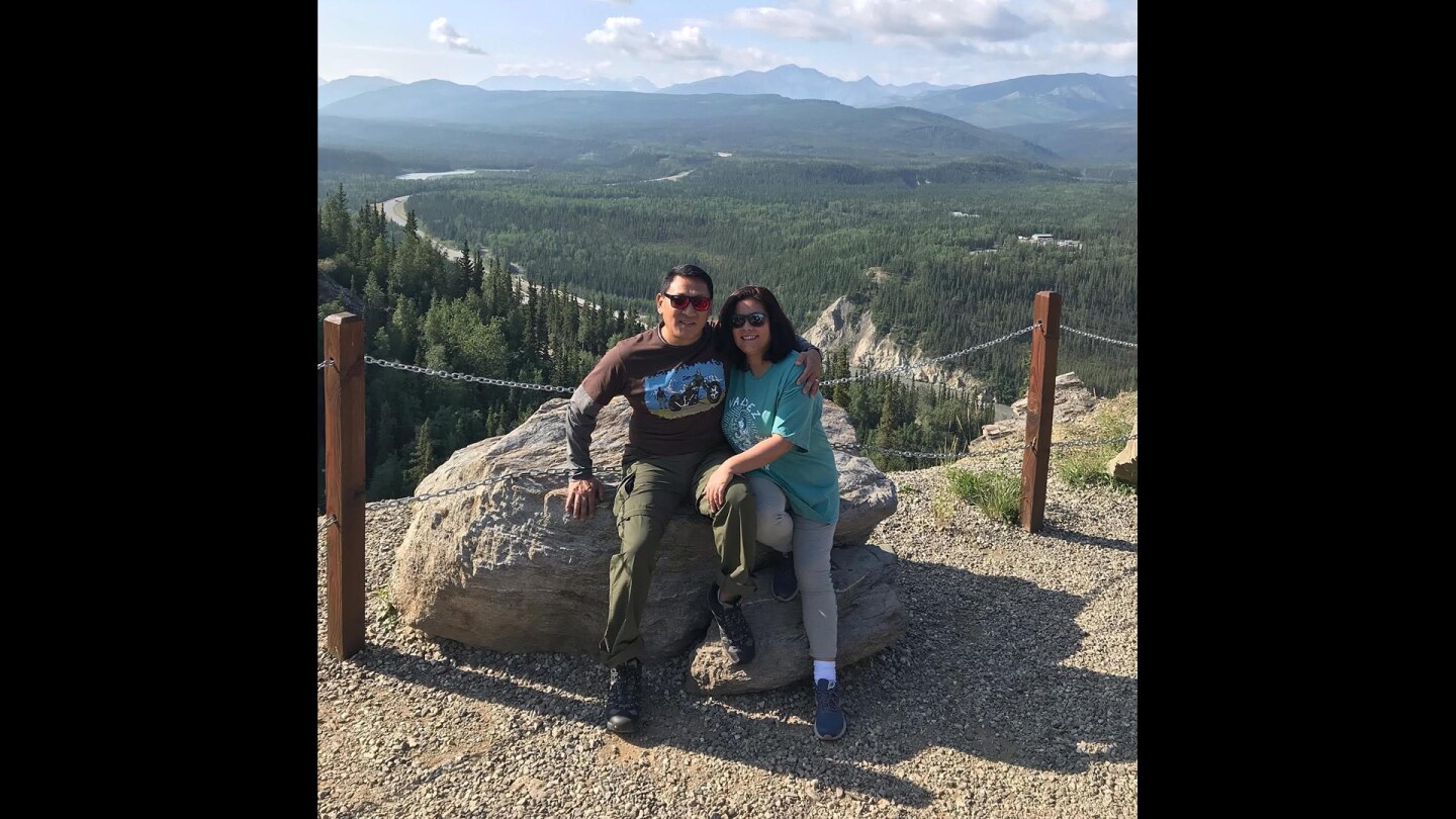 A man and a woman smile at the camera at the top of a hill