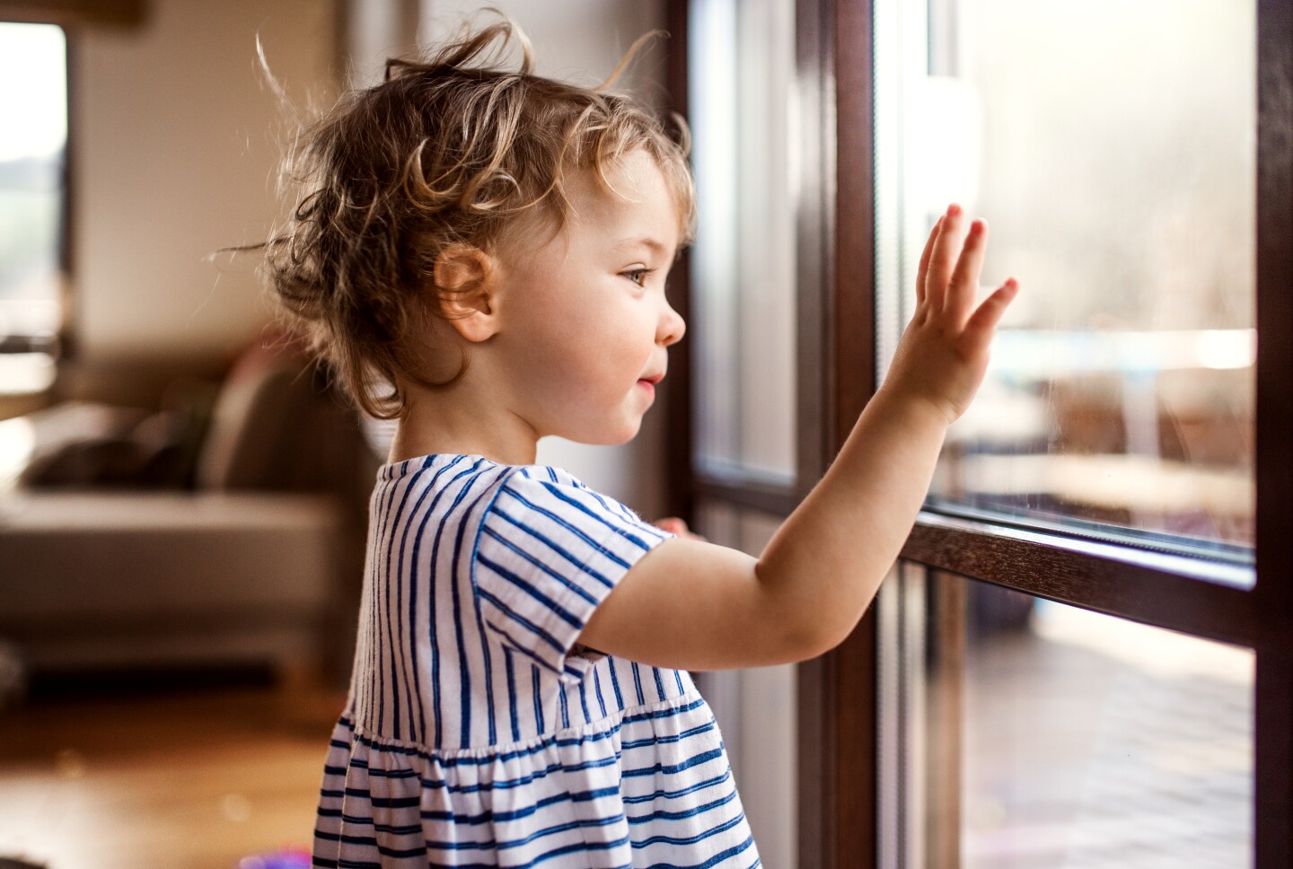A small child looks at their reflection on a window.