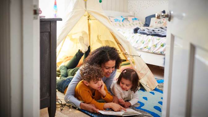 A mother and children read in an indoor tent.